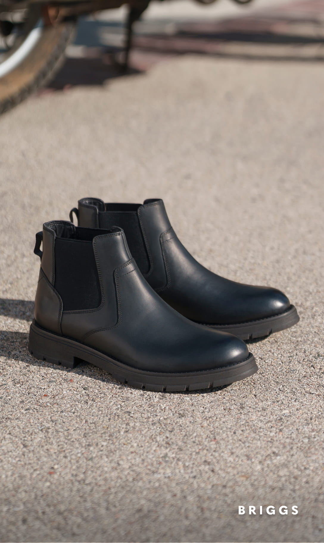 Men's Boots category. Image features the Briggs Plain Toe Chelsea Boot in Black Waxy on concrete flooring.