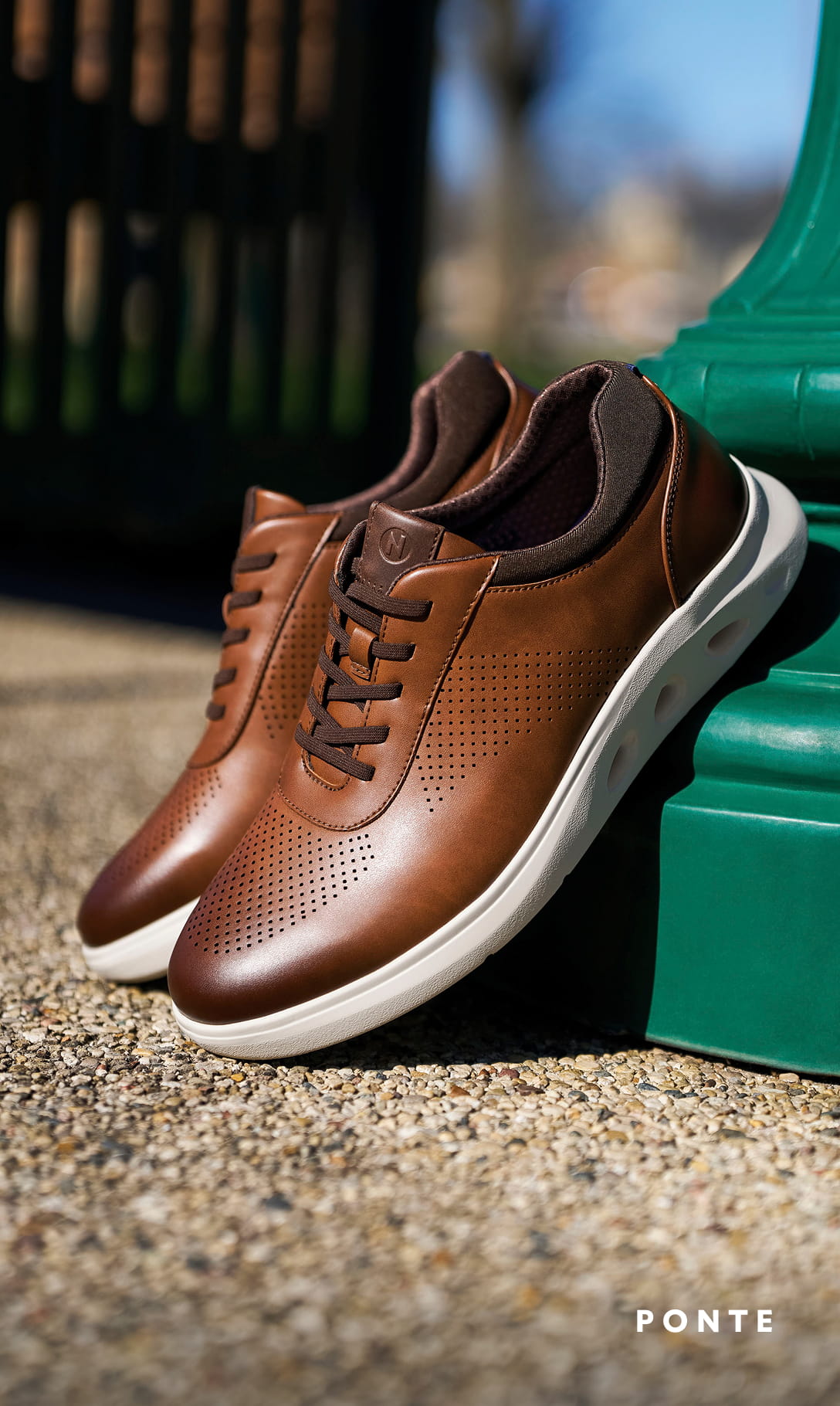 Men's Casual Shoes category. Image features the Ponte Perf Toe Sneaker in cognac leaning against a green lamp post.