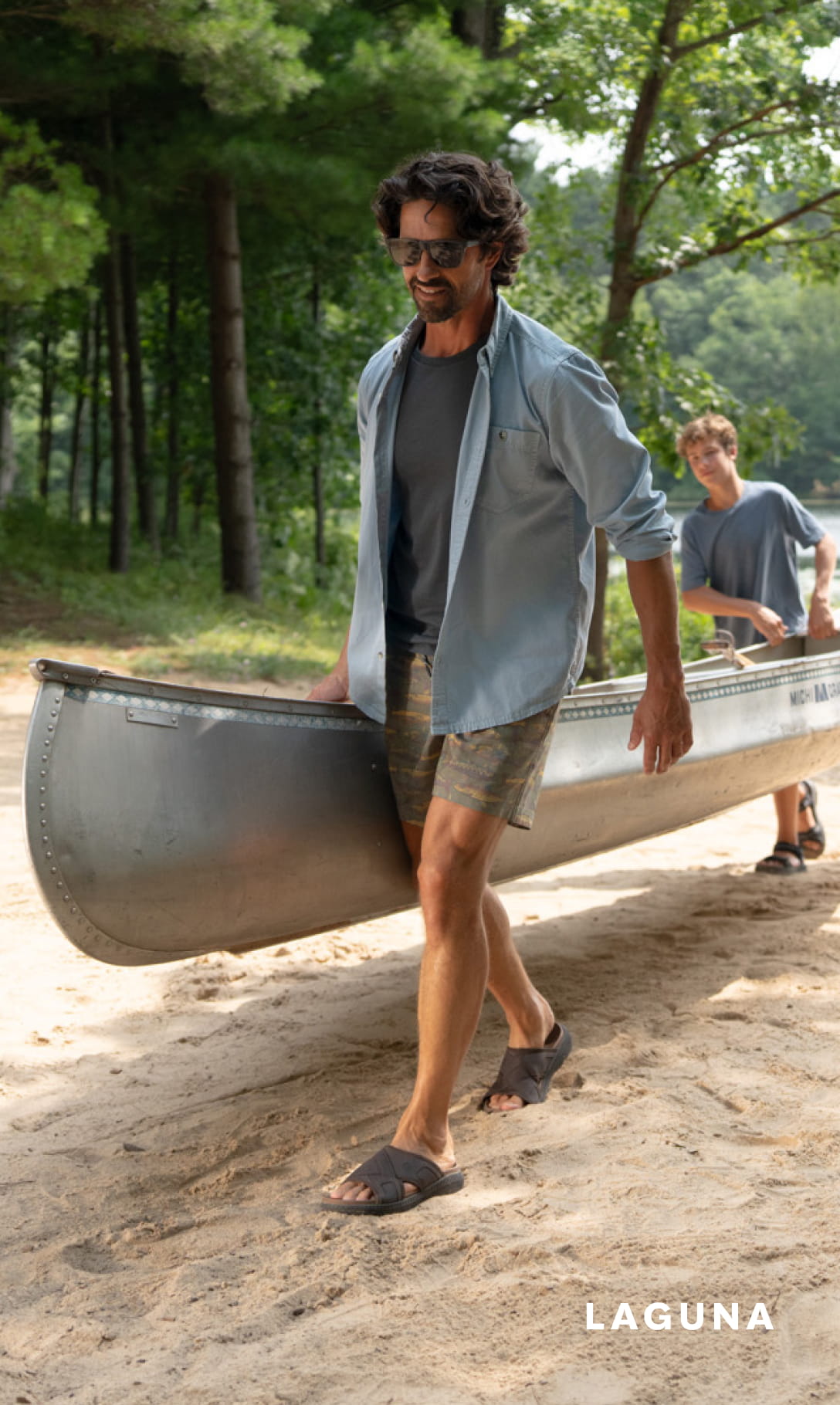 Shoes for Men view all category. Image features a man and son carrying a canoe in sandals.